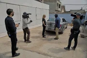 Crew filming Mariana van Zeller while she interviews a masked subject by vehicle.