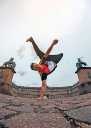 Parkours-K&uuml;nstler Andreas Haug - im Bild am Schlossplatz Stuttgart - &uuml;berwindet mit seinem K&ouml;rper per Salto, Schraube und Sprung im Weg stehende Barrieren effizient.