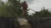PAPUA NEW GUINEA - Hazen paddling with a large paku he caught, which will be presented as a gift to the villagers he is heading towards.
