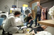 In der W&auml;scherei sichern Dr. Philipp Hartmann (Jakob Graf, l.) und Jerry Paulsen (Peter Marton, M.) erste Spuren, w&auml;hrend Benedikt Beissl (Andreas Giebel, r.) den Tatort &uuml;berblickt.