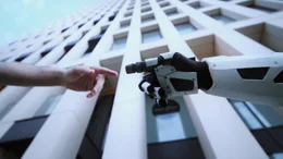 Das Bild zeigt die Begegnung zwischen einer menschlichen Hand und einer Roboterhand, ein h&auml;ufig verwendetes Motiv, das f&uuml;r Innovation und die Verschmelzung von Technologie und menschlicher Existenz steht.