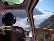 Helicopter pilot seen from behind above a glacier