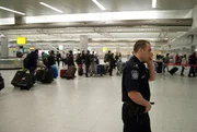 Jamaica, New York, USA: Customs and Border Protection officer Joe Finn takes a call while travelers wait in line at John F. Kennedy International Airport.