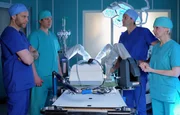 W&auml;hrend der neue OP-Roboter bei Dr. Martin Stein (Bernhard Bettermann, 2.v.re.) und Dr. Kathrin Globisch (Andrea Kathrin Loewig, re.) auf regelrecht verspielte Begeisterung trifft, m&uuml;ssen Chefarzt Dr. Kai Hoffmann (Julian Weigend, li.) und Dr. Brentano (Thomas Koch, 2.v.li.) daf&uuml;r sorgen, dass der Alltag in der Sachsenklinik weitergeht. Dr. Stein muss weiterhin auch ohne Roboter operieren und Dr. Globisch soll sich in robotergest&uuml;tzte OP-Techniken einarbeiten.