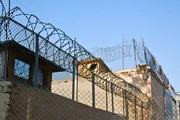 Old brick wall of prison with barbwire background