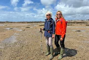 Tamina Kallert (r) wandert mit der Geografin und Wanderf&uuml;hrerin Trudie Hairon-Trox bei Ebbe durch die K&ouml;nigliche Bucht von Grouville.