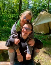 Giuliana legt sitzt hinter Patrick und legt die Arme um ihn.