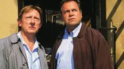 Stefan Kehler (Wolfgang Bathke, re.) und der Drogeriebesitzer Paul Borowski (Raimund Gensel) sind dabei, als in der abgebrandten Drogerie die Leiche einer Frau gefunden wird.