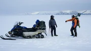 Zwei Personen unterhalten sich in der N&auml;he von Schneemobilen