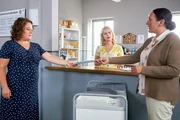 Frau Hiermeier (Annabel Faber, l.), die Urlaubsvertretung von Frau Stockl, bringt den Kolleginnen Lange (Sarah Thonig, M.) und Grasegger (Ursula Maria Burkhart, r.) ein Phantombild des zur Fahndung ausgeschriebenen Mannes.