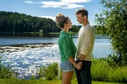 Lea (Vita Tepel) und Mik (Florian Frowein) stehen sich am gr&uuml;nen Ufer eines schillernden Gew&auml;ssers gegen&uuml;ber, und sehen sich verliebt in die Augen.