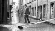 Hochwasser in der K&ouml;lner Altstadt am 25. Februar 1970: Ein Mann geht auf einem Steg aus Holzbohlen &uuml;ber eine der &uuml;berschwemmten Stra&szlig;en im Martinsviertel der K&ouml;lner Altstadt. Das Hochwasser erreichte an diesem Tag einen Pegelstand von 8,87 Metern.