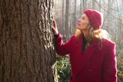Einstein Moderatorin Kathrin H&ouml;negger blickt zu einem Baumstamm in einem Schweizer Wald.