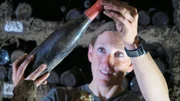 Winzerin Theresa Breuer kontrolliert im Weinkeller ihres Familienbetriebs in R&uuml;desheim eine gereifte Flasche - zwischen jahrhundertealter Weintradition und den Herausforderungen des Klimawandels.
