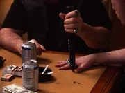 Ein Mann stach ein Messer zwischen den Fingern der Hand eines anderen Mannes in den Tisch