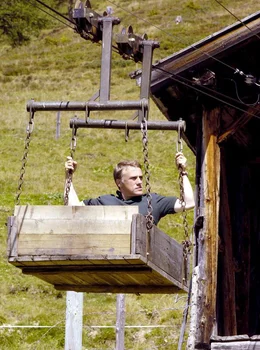 Weil Helmut Bahr (Christoph Waltz) mit seinem verletzten Bein den Abstieg von der Alm nicht schafft, hilft ihm der Bauer Hias mit seinem Seilbahn-W&auml;gelchen aus.