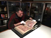 Rob examines ancient Irish text in the Book of Kells.