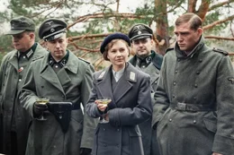 In einem nationalsozialistischen Durchgangslager stationierte SS-Angeh&ouml;rige (Felix von Bredow, Ingo H&uuml;lsmann, David Sch&uuml;tter) haben sich zu einem Picknick im Freien zusammengefunden.