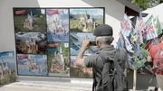 Ein Tourist vor Plakaten zum Schloss Neuschwanstein.