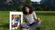 Moderatorin Siham El Maimouni mit einem Bild von K&ouml;nig Ludwig vor dem Schloss Neuschwanstein