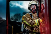 Ein Feuerwehrmann der Berufsfeuerwehr Duisburg in Schutzkleidung und abgelegter Atemschutzmaske steigt in ein Einsatzfahrzeug ein. - Die Meldung klingt zun&auml;chst unkompliziert: Eine Gartenh&uuml;tte brennt. Doch dann wird es kompliziert &ndash; der Anrufer kann keine feste Adresse nennen. Angespannt suchen die Einsatzkr&auml;fte der Feuerwehr Duisburg nach der Einsatzstelle.