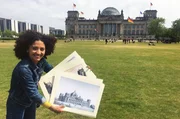 Moderatorin Siham El Maimouni zeigt einige alte Stiche vor dem Reichstagsgeb&auml;ude in Berlin.