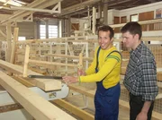 Ein Zimmermann erkl&auml;rt Willi Weitzel seine Arbeit. Hier entstehen Holzbalken f&uuml;r die W&auml;nde eines Fertighauses.