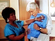 Delores (Delores Hall, l.) stellt bei der Anprobe fest, dass ihr gestrickter Pullover nicht ganz die passende Gr&ouml;&szlig;e f&uuml;r Dr. Sloan (Dick Van Dyke, r.) hat.