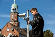 Henk Cassens (Maxim Mehmet) bringt eine &Uuml;berwachungskamera f&uuml;r das neue Sicherheitskonzept der Polizei Leer an.