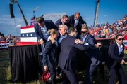 Butler, Pennsylvania &ndash; 13. Juli: Agenten des US-Geheimdienstes entfernen den republikanischen Pr&auml;sidentschaftskandidaten und ehemaligen Pr&auml;sidenten Donald Trump mit Blut im Gesicht von der B&uuml;hne w&auml;hrend einer Wahlkampfveranstaltung bei der Butler Farm Show Inc. in Butler, Pennsylvania, am Samstag, dem 13. Juli 2024. Trump teilte sp&auml;ter mit, dass eine Kugel w&auml;hrend des Attentats einen Teil seines Ohrs durchschlagen habe.