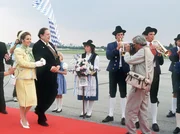Standesgem&auml;ss wird die K&ouml;nigin von Mandalia (Michaela May) vom Ministerpr&auml;sidenten (Georg Marischka, links) auf dem Flughafen in Empfang genommen. F&uuml;r Fotograf Herbie (Dieter Hildebrandt) ist das ideal.