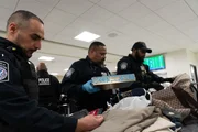 Mehrere CBP-Beamte durchsuchen das Gep&auml;ck eines Reisenden, nachdem darin Waffenbestandteile gefunden wurden. (National Geographic)