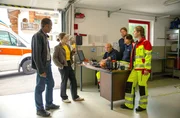 Vor Hauptkommissar Jerry Paulsen (Peter Marton, l.) und Kommissarin Sophia Strasser (Katharina Leonore Goebel, r.) halten die Sanit&auml;ter Ritschi (Peter Finsterwalder, M.), Bruno (Timo Gasteger, 3.v.r.), Bertha (Vanessa Jung, 2.v.r.) und Luise (Sophie R&ouml;hrmoser, r.) zusammen. Doch die Kommissare haben einen Zettel mit einer Drohung bei einem der Sanit&auml;ter gefunden.