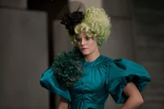 Katniss' und Peetas Betreuerin ist Effie Trinket (Elizabth Banks). Sie tr&auml;gt immer eine Per&uuml;cke in einer knalligen Farbe und dazu passendes Makeup ...