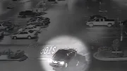 Eine n&auml;chtliche &Uuml;berwachungsaufnahme zeigt ein Fahrzeug, das an einer 'STOP'-Markierung auf einem Parkplatz vorbeif&auml;hrt.
