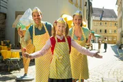 Lucy (Valerie/Violetta Arnemann, mitte) und ihre Eltern, Pietro (Kostja Ullmann, links) und Nadine (Franziska Wulf, rechts) werden vor der Eisdiele f&uuml;r einen  Zeitungsartikel fotografiert.