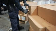 Ein CBP-Beamter versucht, einen Karton zu &ouml;ffnen, der Plastikrollen enth&auml;lt, die in einer Lieferung gefunden wurden.