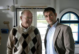 Unternehmer Kolditz (Dieter Mann) stattet Hans-Werner (Heikko Deutschmann) einen Besuch auf seinem Hausboot ab.