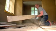 Bauherr Daniel Hoherz beim Entfernen der alten Dielen im Wohnzimmer der Alten Apotheke in Nusse.