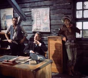 Der Ganove Forrester (Anthony Steel, M.) l&auml;sst sich &uuml;ber die Lage informieren. Besondere Auftr&auml;ge vergibt er an seinen Vertrauten Luca (Klaus Kinski, r.).