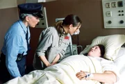 Schnoor (Uta Prelle, li.) hat Mitleid und deswegen Kalle (Isabelle H&ouml;pfner, Mi.) erm&ouml;glicht, Nancy (Livia S. Reinhard), die mit einem Zuckerkoma auf der Krankenstation liegt, zu sehen.