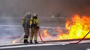 Two firefighters extinguish a burning truck in Dresden.