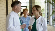 Dr. Roland Heilmann (Thomas R&uuml;hmann, links) und Dr. Lea Peters (Anja Nejarri, rechts) haben die anstrengende OP beendet. Respektvoll tauschen sie sich &uuml;ber ihre fachlichen Kompetenzen aus. Rolands Frau Pia (Hendrikje Fitz, Mitte) beobachtet Roland genau. Sie hatte gro&szlig;e Sorgen, dass er sich nach seinem Unfall und den nachfolgenden Operationen zu viel zumutet. Doch Roland beteuert Pia, dass es ihm gut geht. Pia glaubt, dass ihre physiotherapeutische Behandlung bei Roland gut anschl&auml;gt.