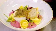 Ein Hauptgericht des "Lenas am See" - Zanderfilet, hausgemachte Parmesanravioli, Erbsenp&uuml;ree, Beurre Blanc - wird auf einem Teller pr&auml;sentiert.