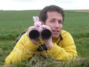 Willi liegt mit dem Fernglas auf der Lauer.