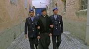 Don Matteo (Terence Hill, M.) wird von zwei Polizisten ins Gef&auml;ngnis gef&uuml;hrt.