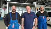 Marcus Thiel, his colleague Florian &ldquo;Blitzi&rdquo; H&ouml;rig, and Tool Shop Manager Mike Streif pose next to an aircraft tractor in the workshop hall of the Atlas Air Service aircraft hangar in Bremen.