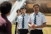 Flugbegleiterin Bonnie Lane (Danielle Pineda, 2.v.l.), Copilot Samuel Dele (Yoson An, 2.v.r.) und Flugkapit&auml;n Brodie Torrance (Gerard Butler, r.) stellen sich nach der Notlandung den aufgeregten Fragen der Passagiere.