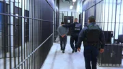 Polizisten begleiten einen Mann im Gef&auml;ngnis.