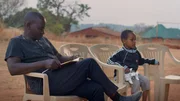 John Mbano ist vertieft in sein Notizbuch. Darin sammelt er alle Informationen zu Songea Mbano.